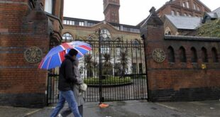 In this file photo dated Sunday, April 29, 2012 shows people walk past gated residential flats in Bow, east London, where the Ministry of Defence have warned residents that surface-to-air missiles could be stationed on their rooftops during the London Olympics. (AP Photo/Sang Tan,File)