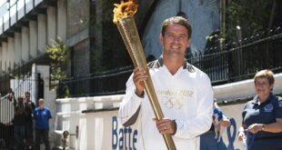 Former England striker Michael Owen poses with the Olympic Torch at Battersea dogs home in London, July 23, 2012. ( REUTERS/Ki Price)