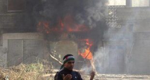 An anti-Syrian regime man reacts in front of flames which rise from a burning shop damaged by Syrian government forces shelling, in Baba Amr neighborhood in Homs province, central Syria, on Sunday Feb. 12, 2012. (AP/Local Coordination Committees in Syria)