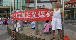 A protester yells anti-Japan slogans as he holds a stick in front of a banner on a commercial street in Wuhan, Hubei province August 18, 2012. (Reuters/Stringer)